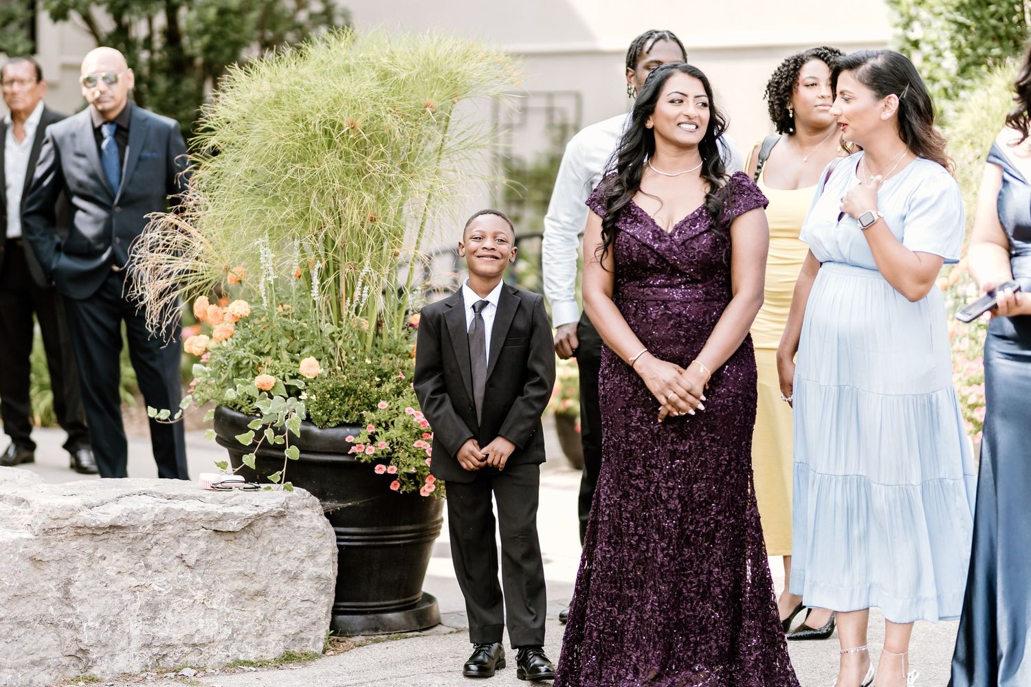 Wedding guests in formal attire gather outdoors for celebration.