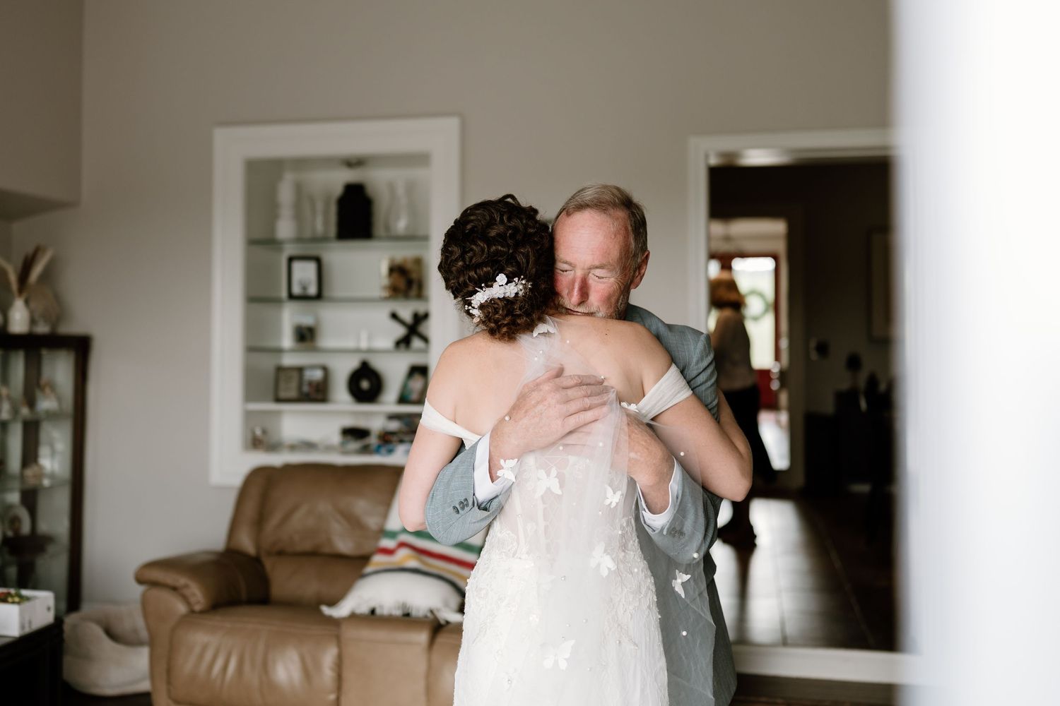 Wedding day moment captured in a bright, modern living room setting.