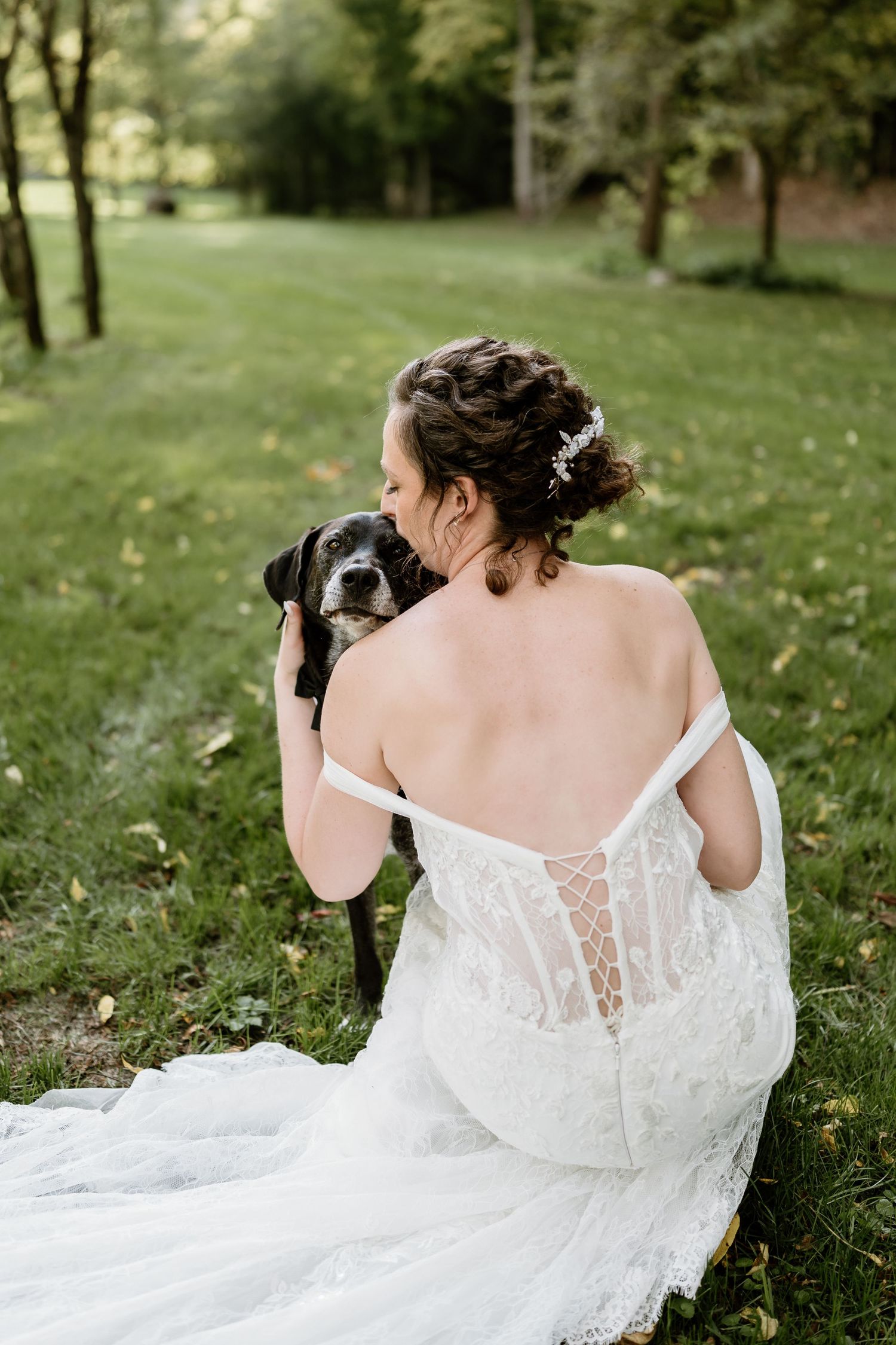 Back view of a bride in a white lace wedding dress with sheer details in an outdoor setting.