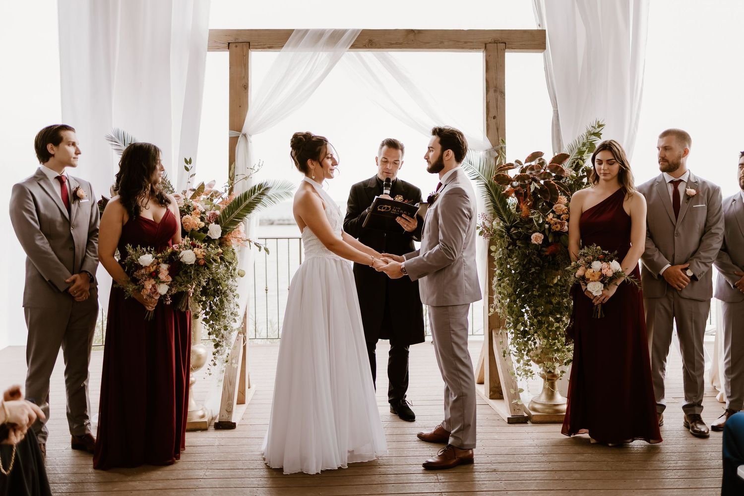 Wedding party and guests gathered in an elegant white-draped venue for the ceremony.