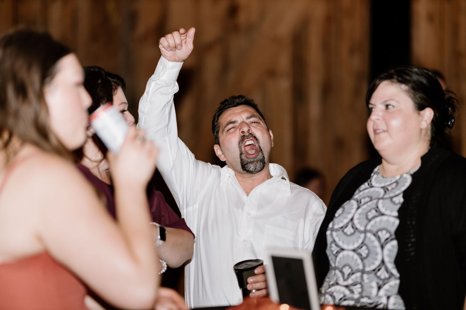 Guests dancing enthusiastically during a lively barn wedding reception celebration.
