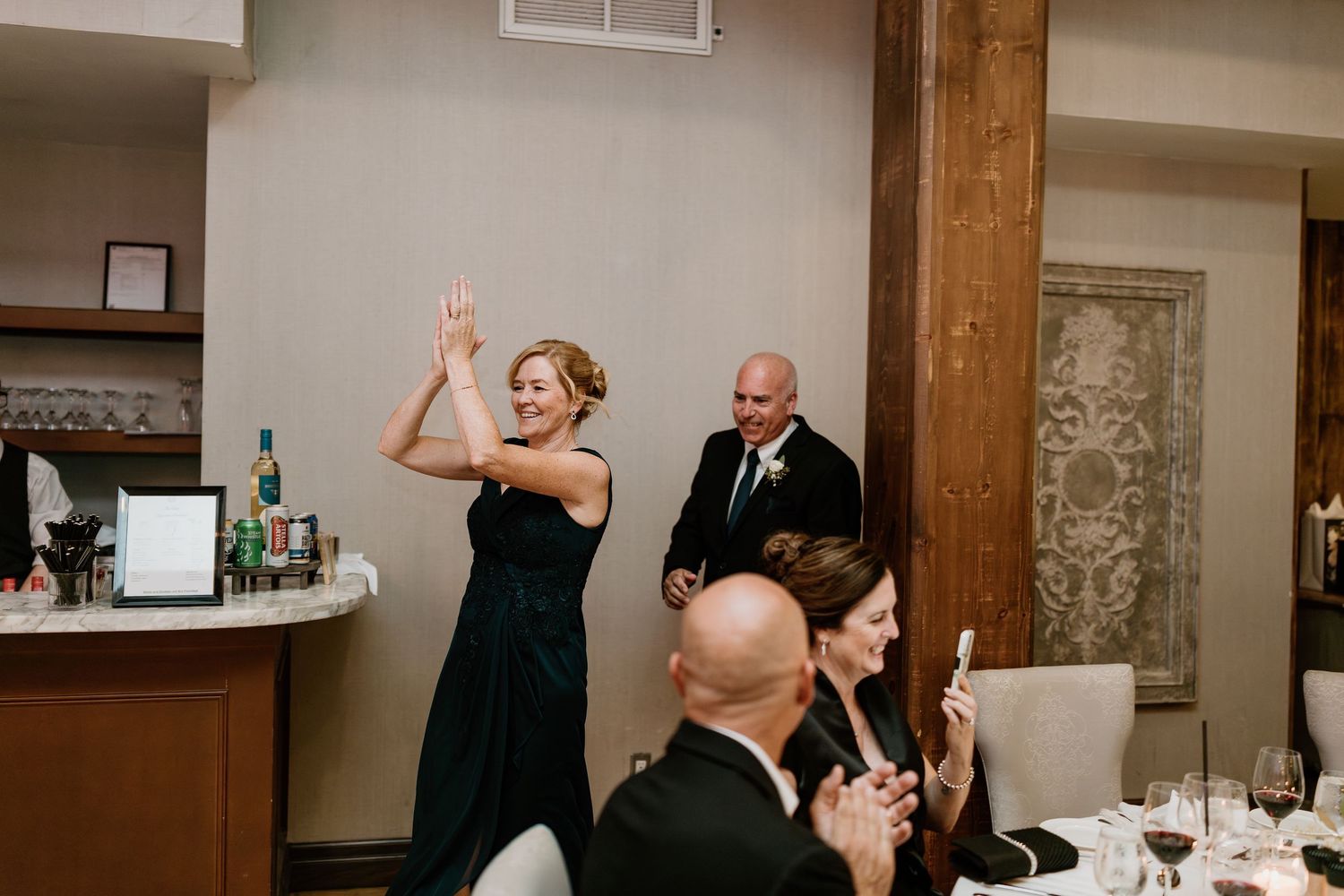 Wedding reception guests dancing and celebrating in rustic indoor venue.