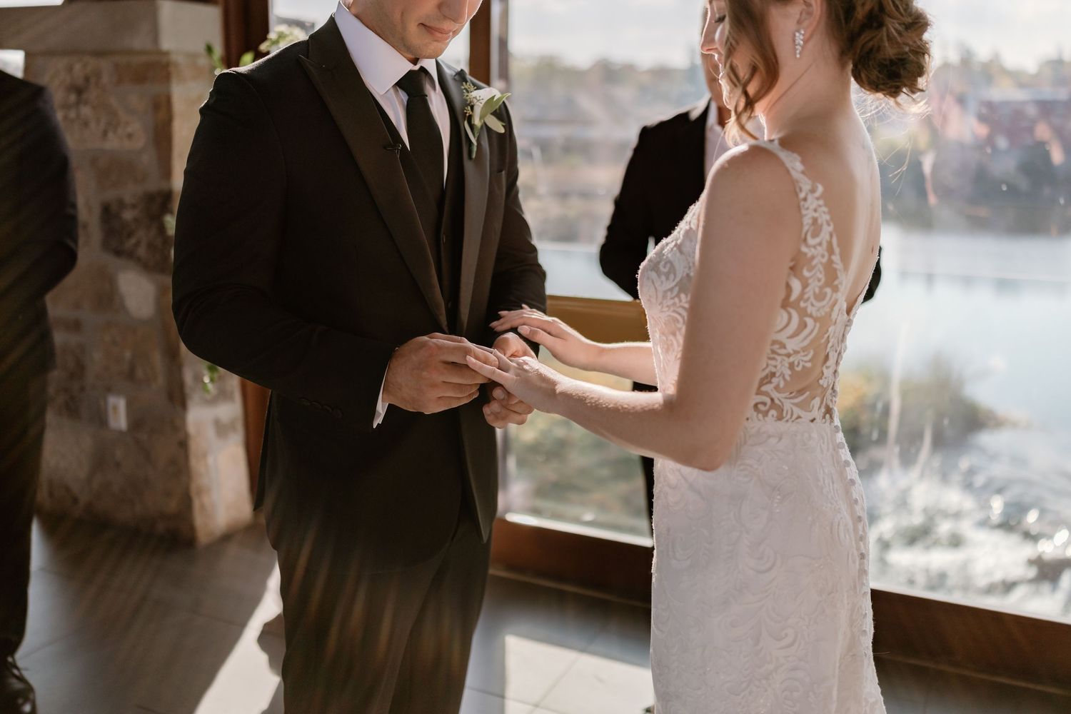 Wedding ceremony with couple reading vows in front of scenic waterfront windows.