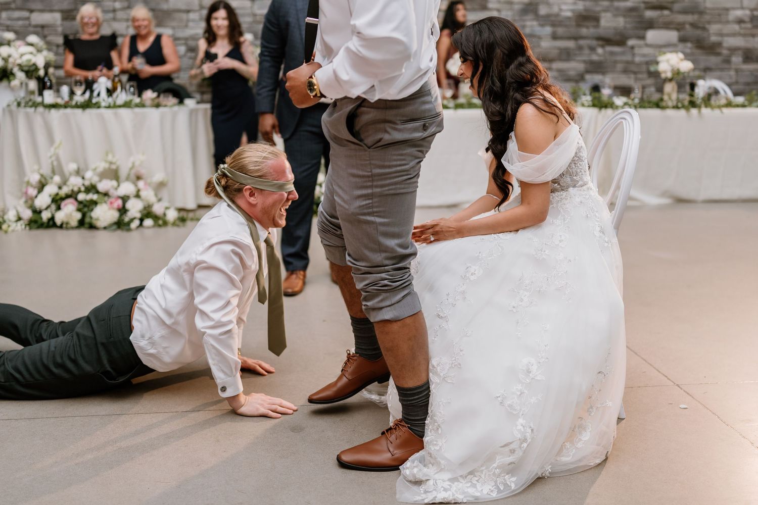Bride and groom share a fun wedding reception moment as a guest playfully crawls on the dance floor.