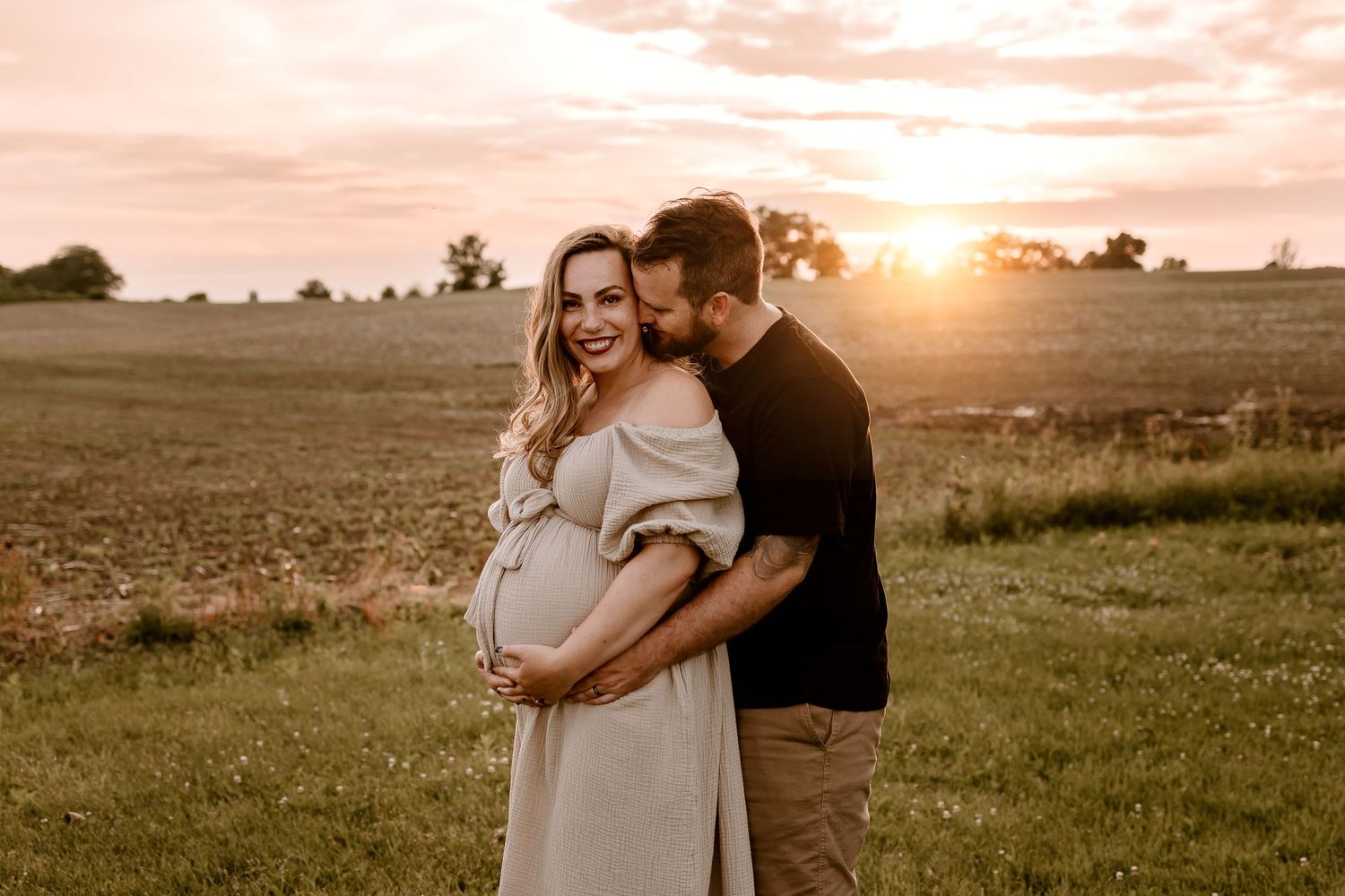 Couple embracing in a golden field during sunset creating a romantic silhouette against the warm sky.