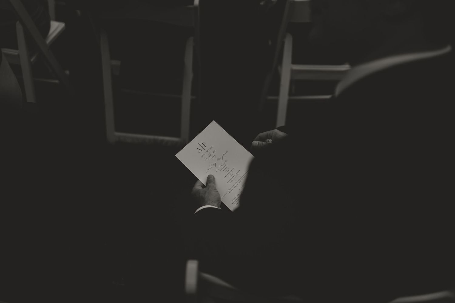 A dark, atmospheric black and white photo of hands holding paper.