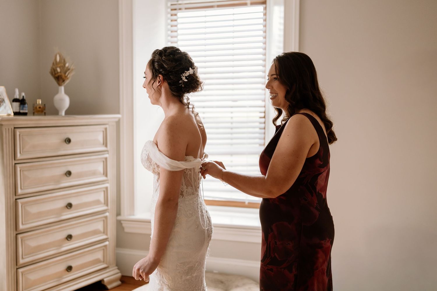 Wedding dress preparations in a bright bedroom with white furniture.
