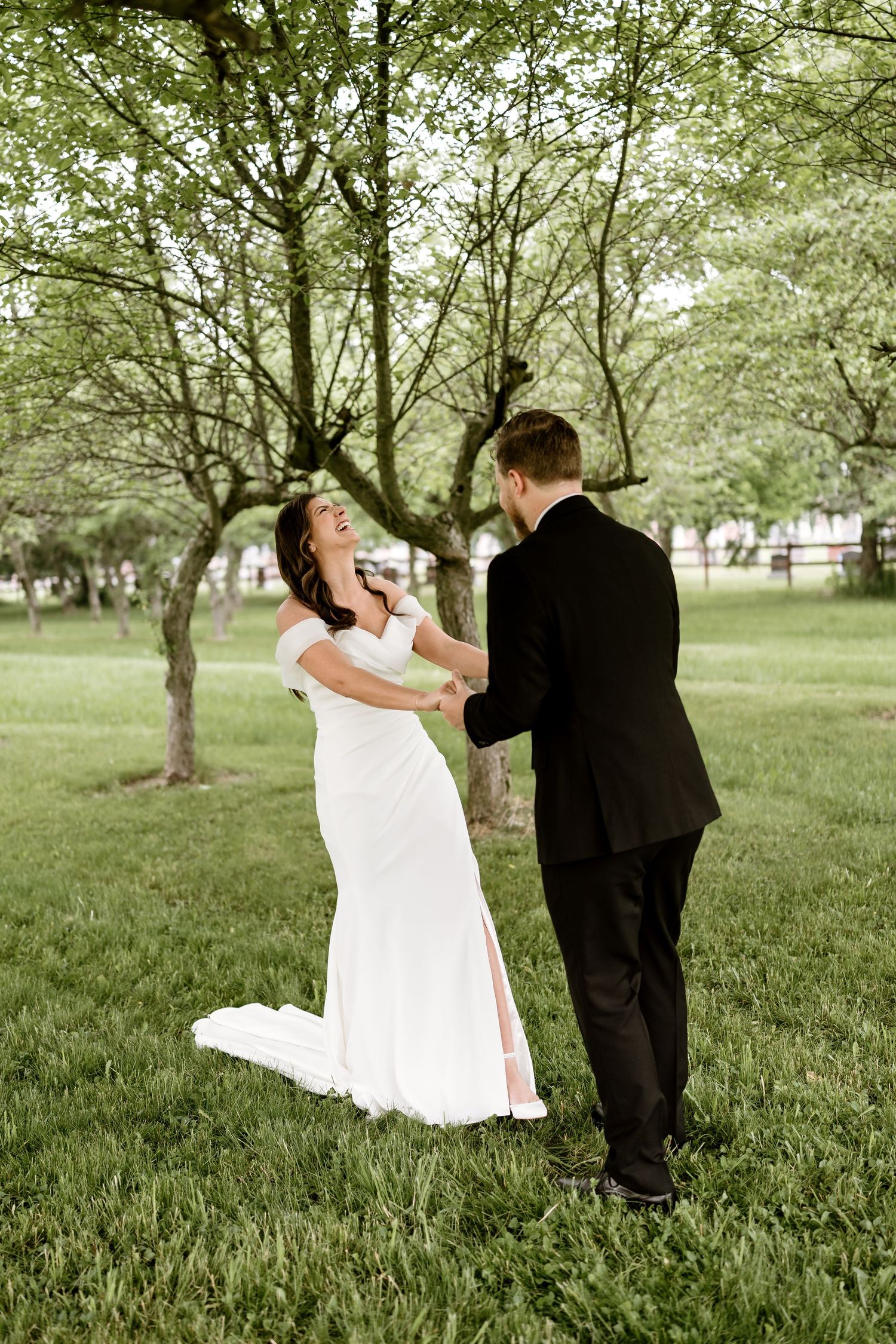 Dancing couple twirls on green grass beneath orchard trees.