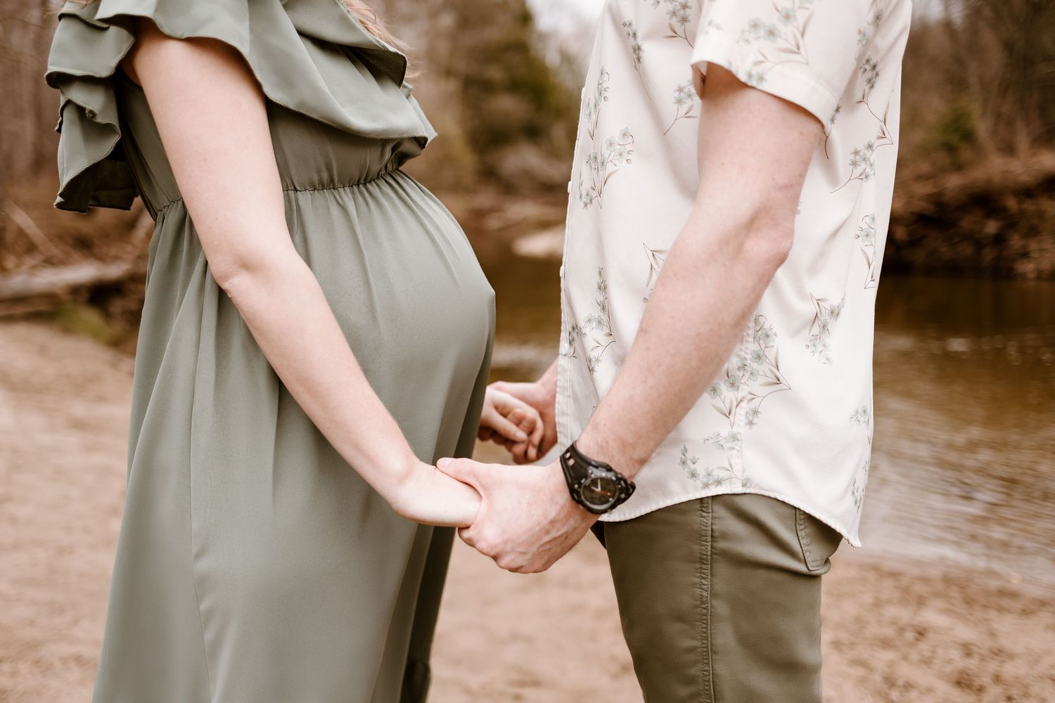 A couple holds hands tenderly while standing together in an outdoor setting.