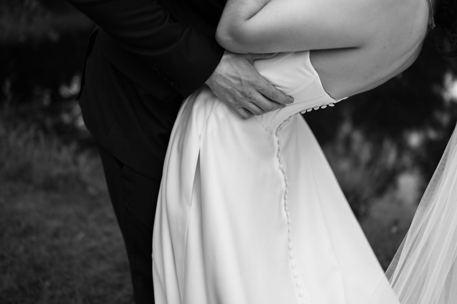 Close-up details of a white wedding dress buttons and fabric.