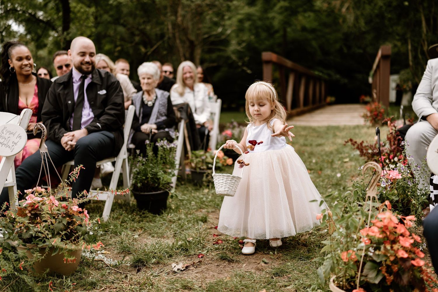 Wedding party poses together in black formal attire on grassy lawn.