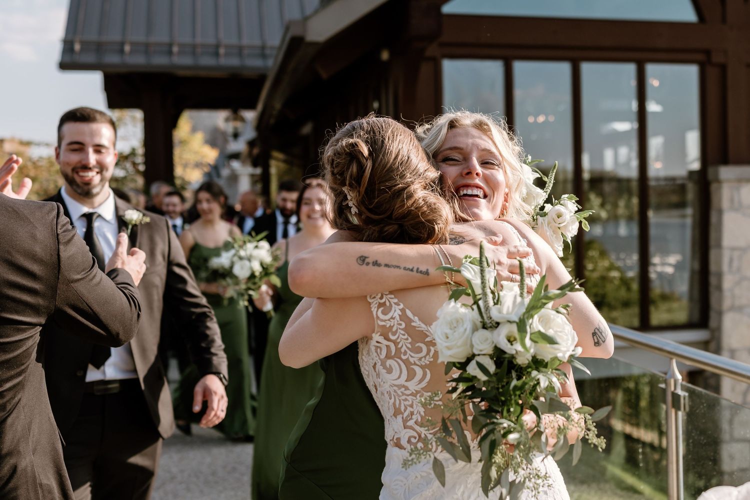 Emotional embrace shared during outdoor wedding ceremony with green-clad bridesmaids.