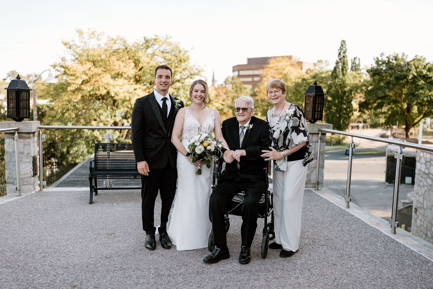 Wedding party poses together on modern outdoor terrace with city backdrop.