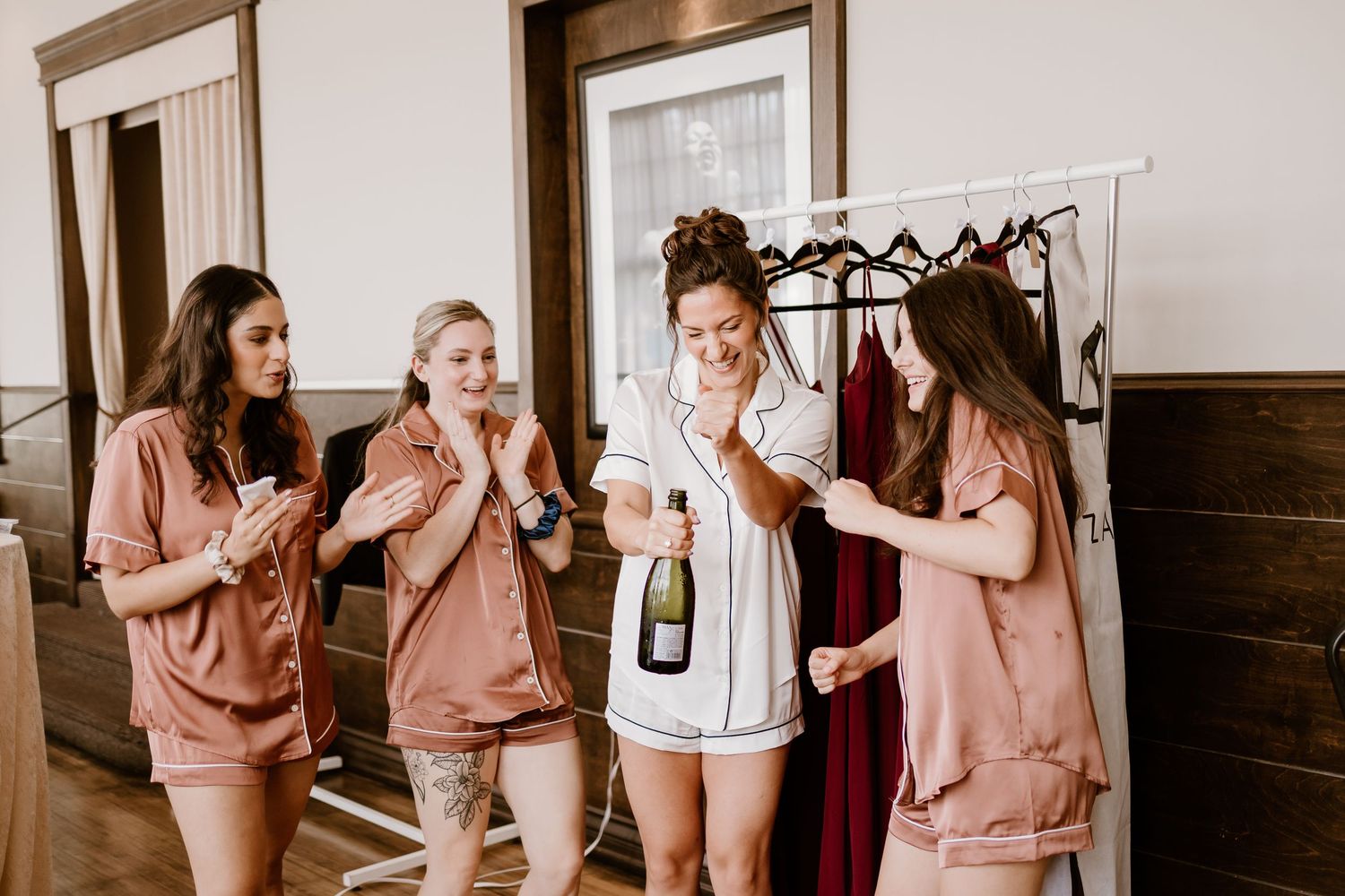 Group enjoying champagne during wedding preparation in matching robes.