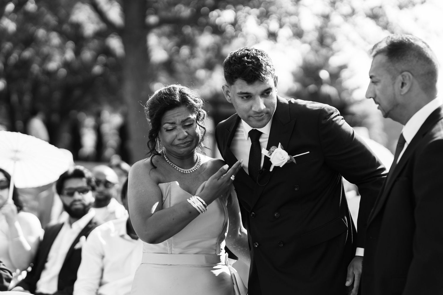 Black and white photo captures emotional moments during outdoor wedding ceremony.