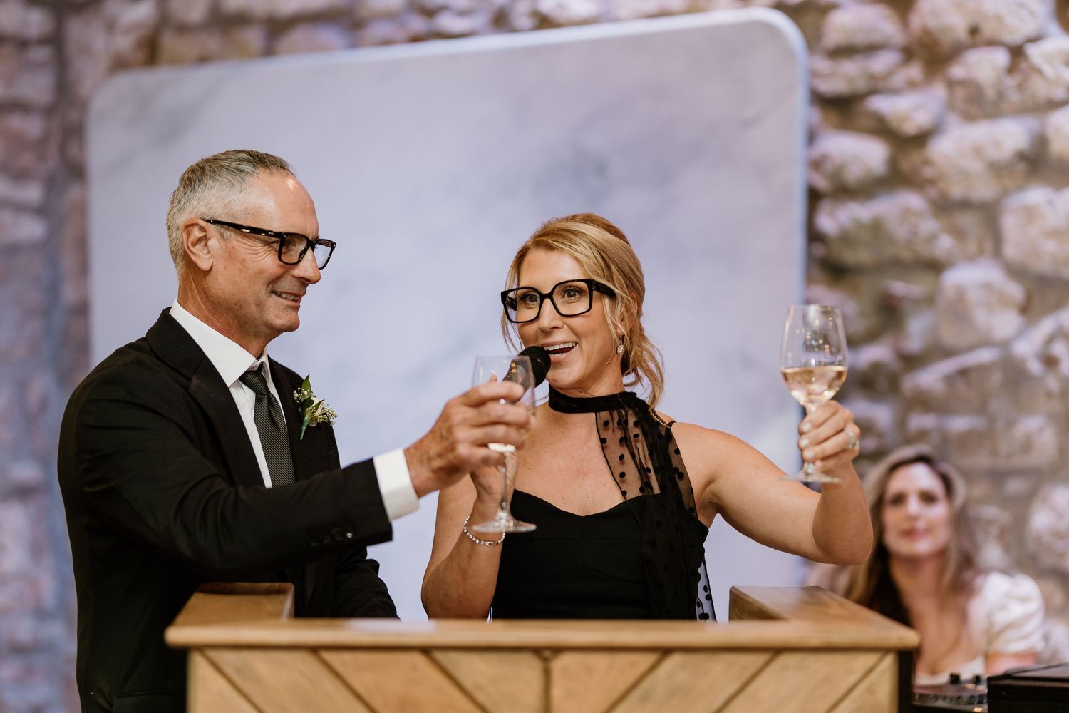 Wedding guests raise glasses in celebratory toasts during reception dinner.