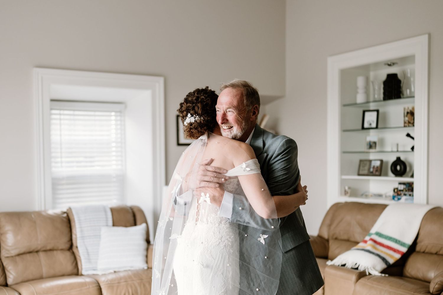 Emotional wedding day scene in a light-filled contemporary home interior.