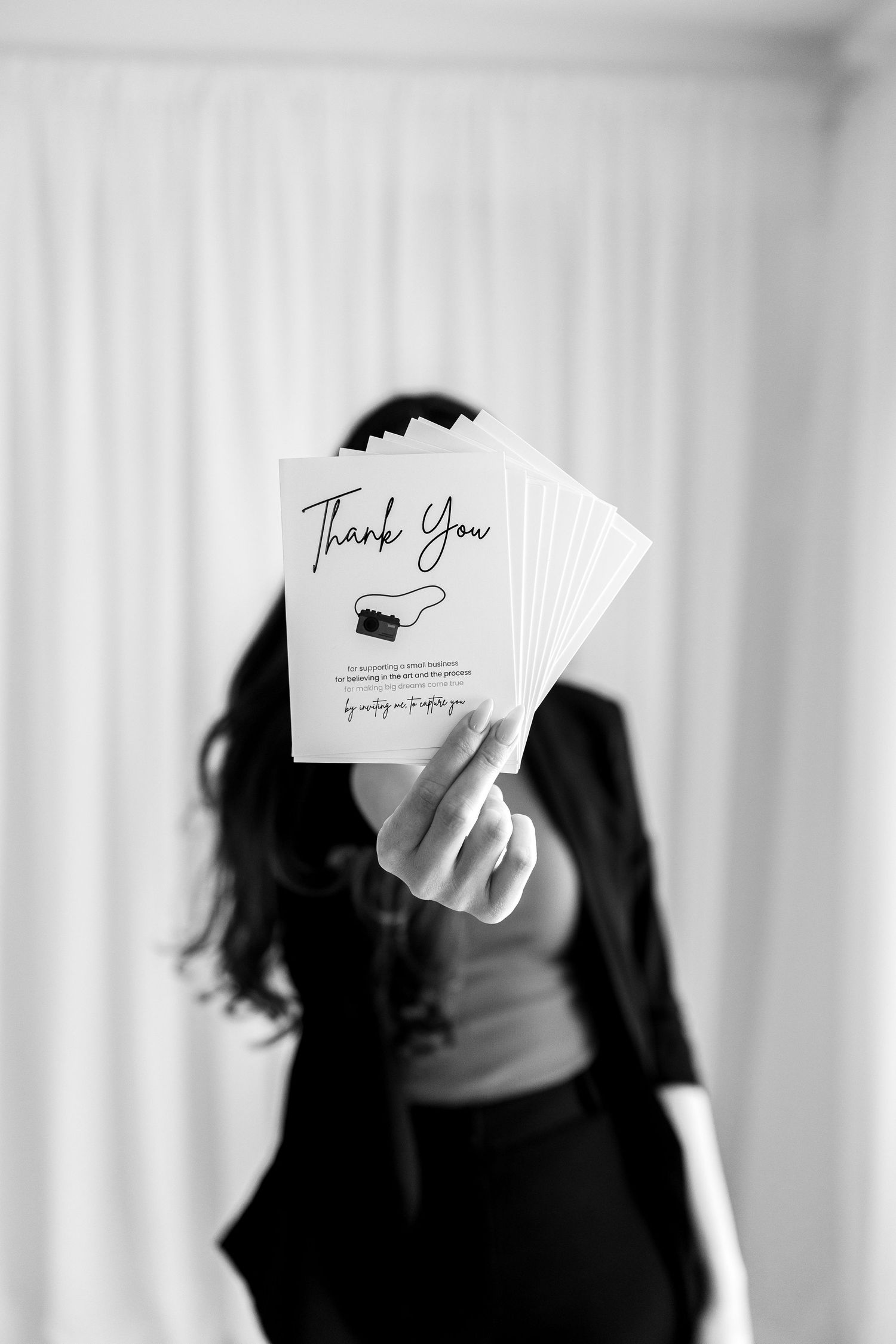 Black and white image of someone displaying business cards with thank you text.