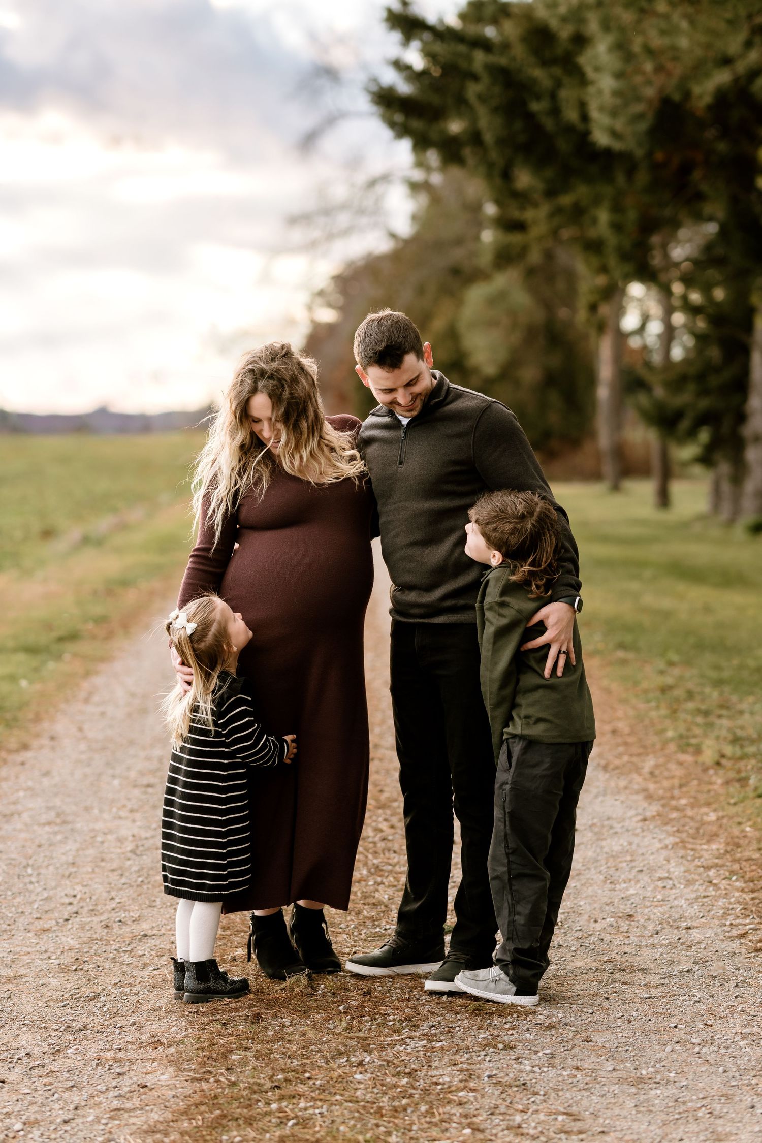 Family members kneeling together on a gravel path during an outdoor photo session.