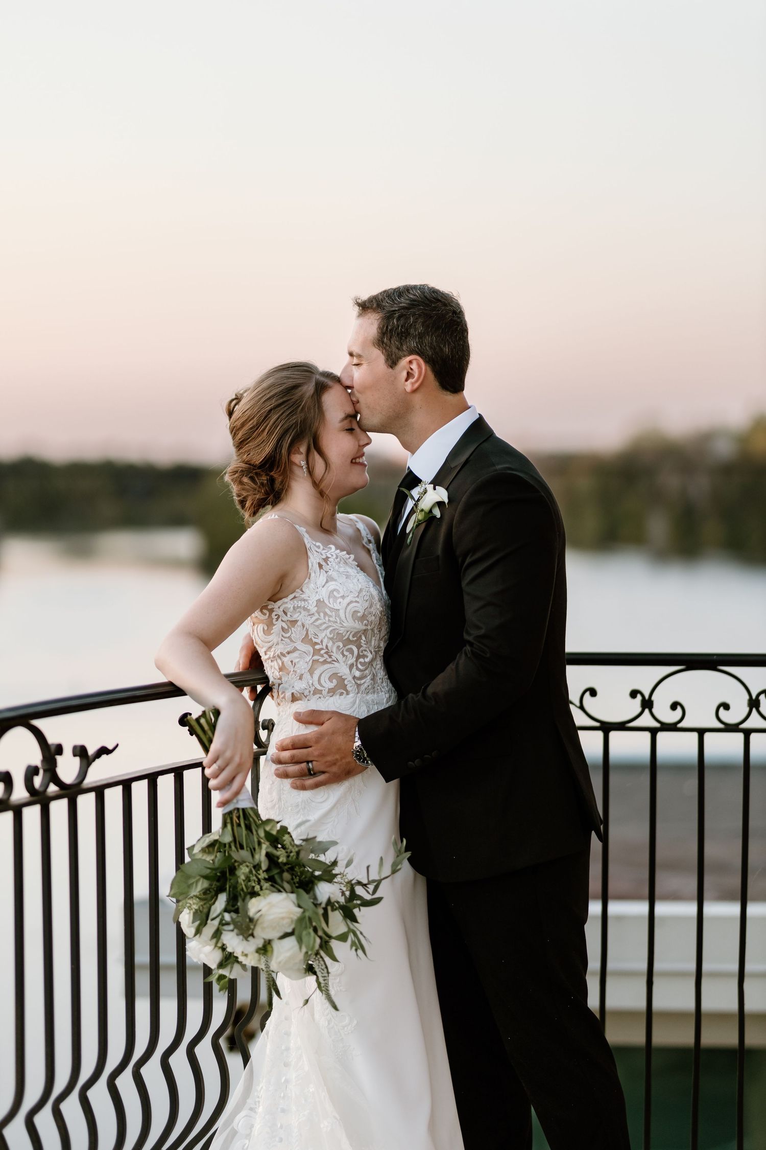 Romantic sunset portraits of couple embracing on balcony with water view.