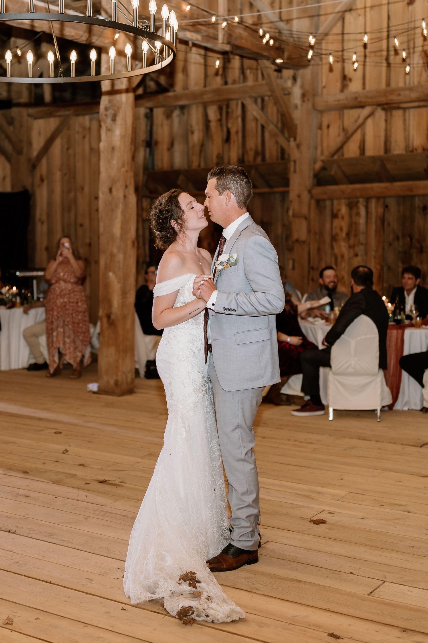 Newlyweds share romantic dance moments in a beautifully lit barn venue.
