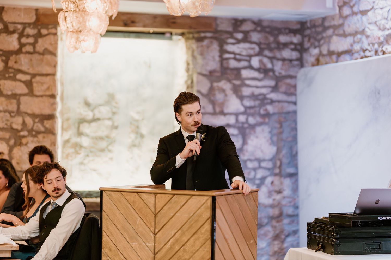 Wedding reception venue features rustic stone walls and wooden decor elements.
