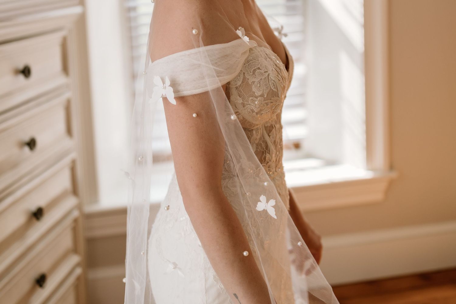 Close-up detail of a delicate white wedding dress with lace detailing.