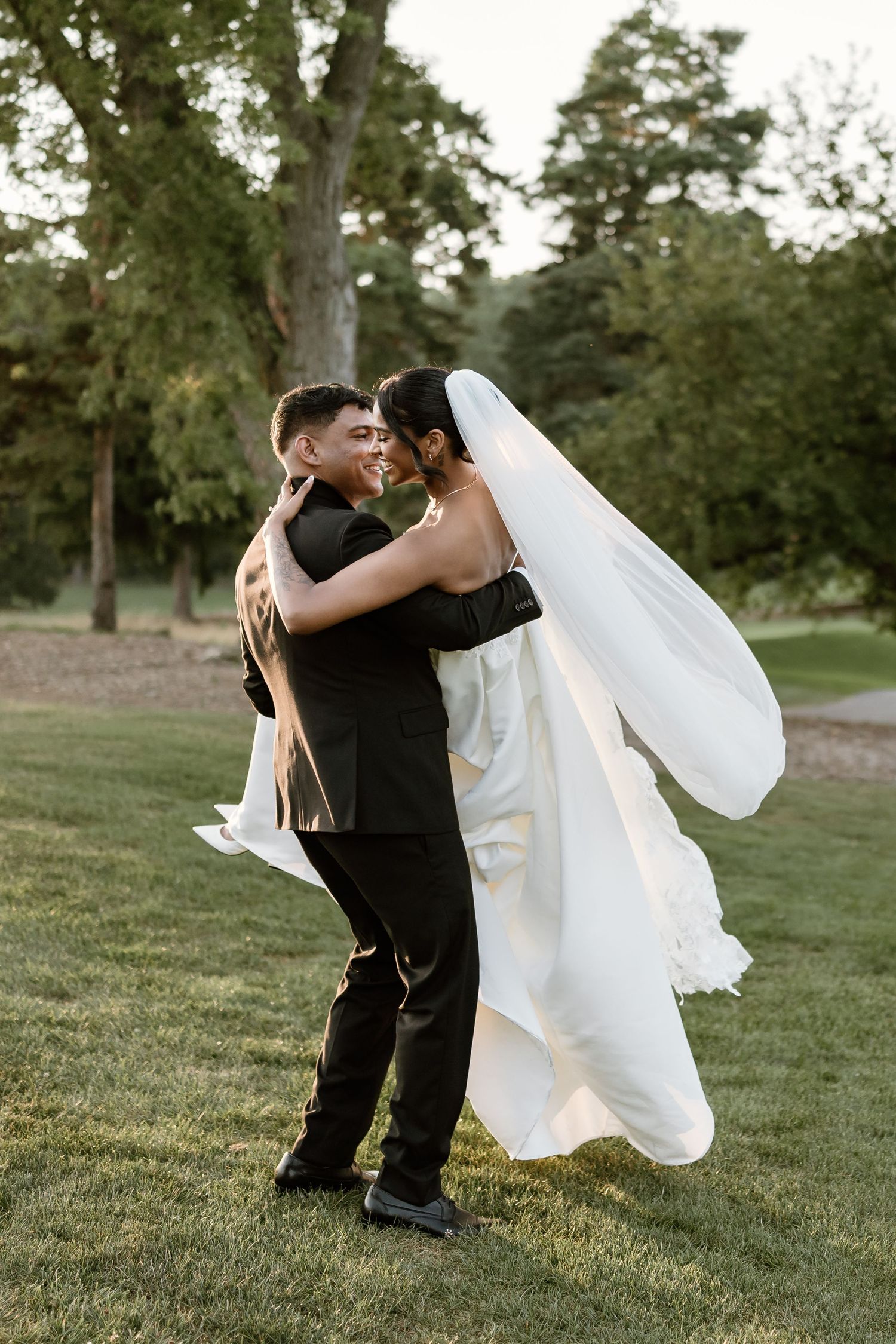 Dancing couple shares intimate moment on grassy hillside during sunset wedding photos.