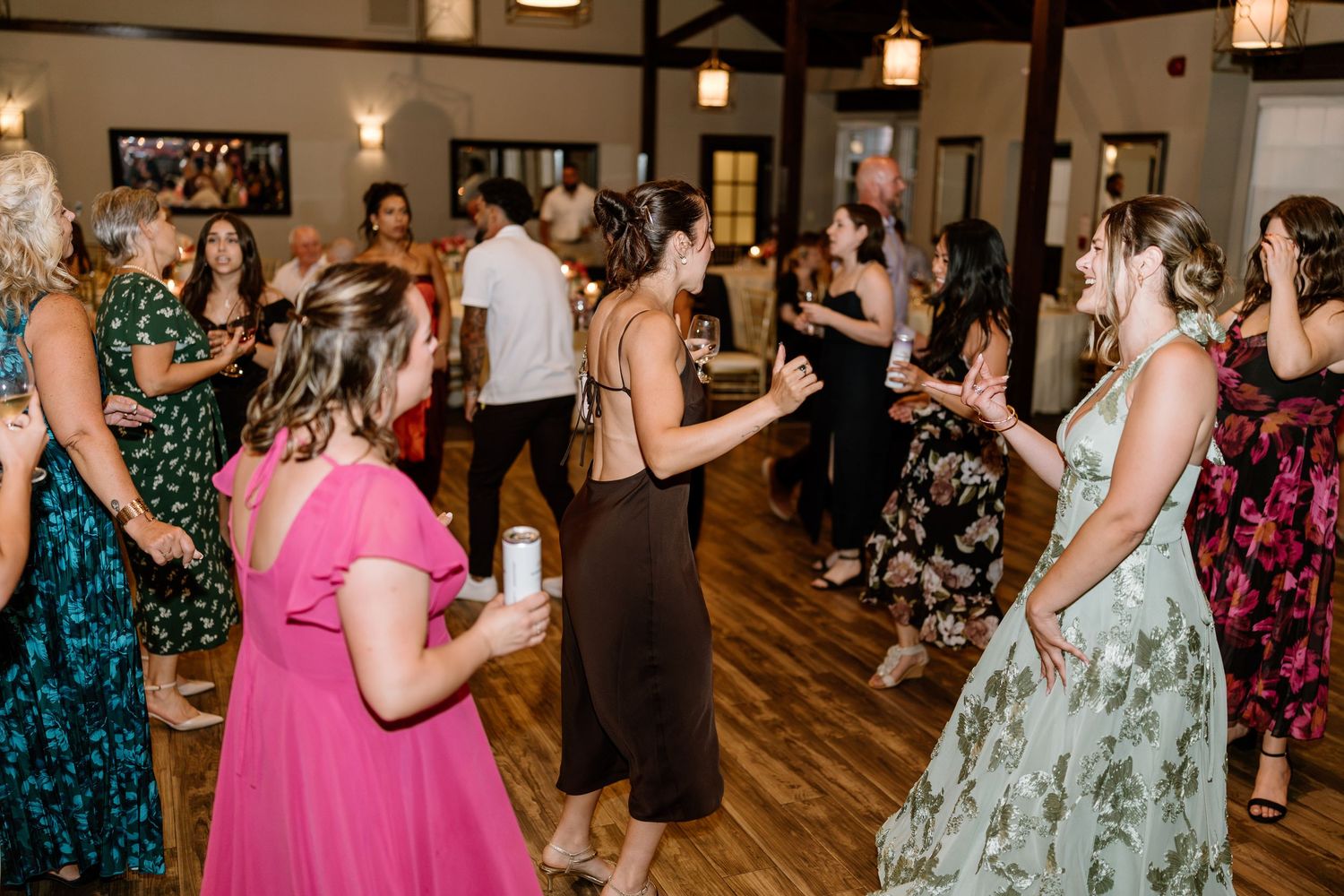 Guests dancing joyfully at a wedding reception in an elegant venue with warm lighting.