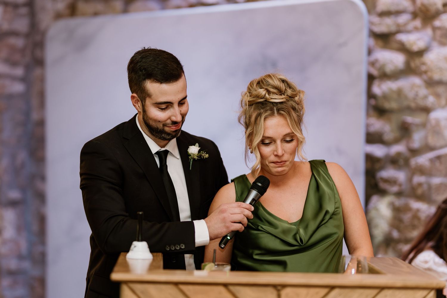 Wedding speech moment in an elegant stone-walled reception venue.