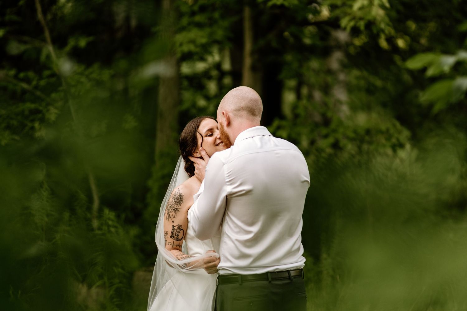 Intimate wedding moment captured in a lush green outdoor setting.