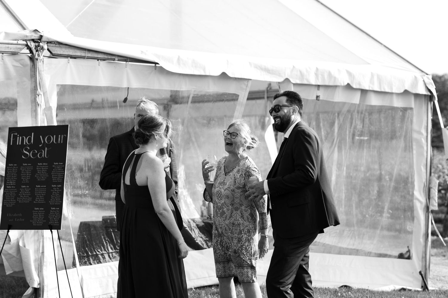 Wedding guests mingling under a white tent during reception celebrations.