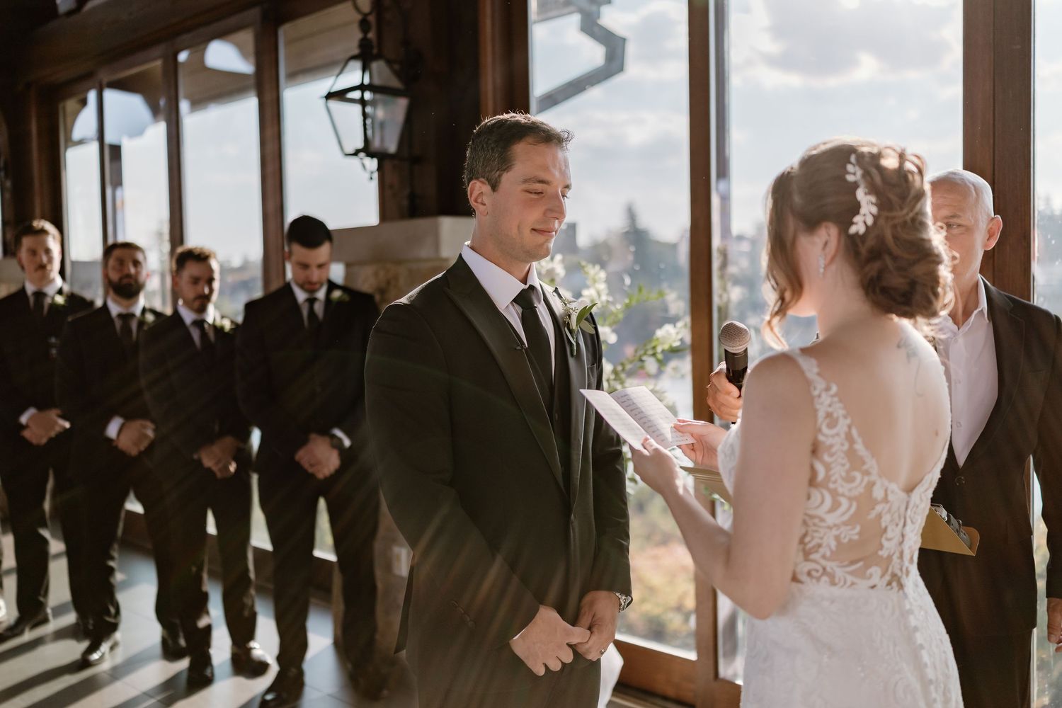 Wedding celebration in progress inside a rustic venue with panoramic window views.