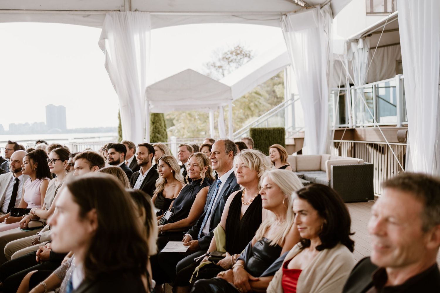 Wedding guests seated in rows during an outdoor tented ceremony.