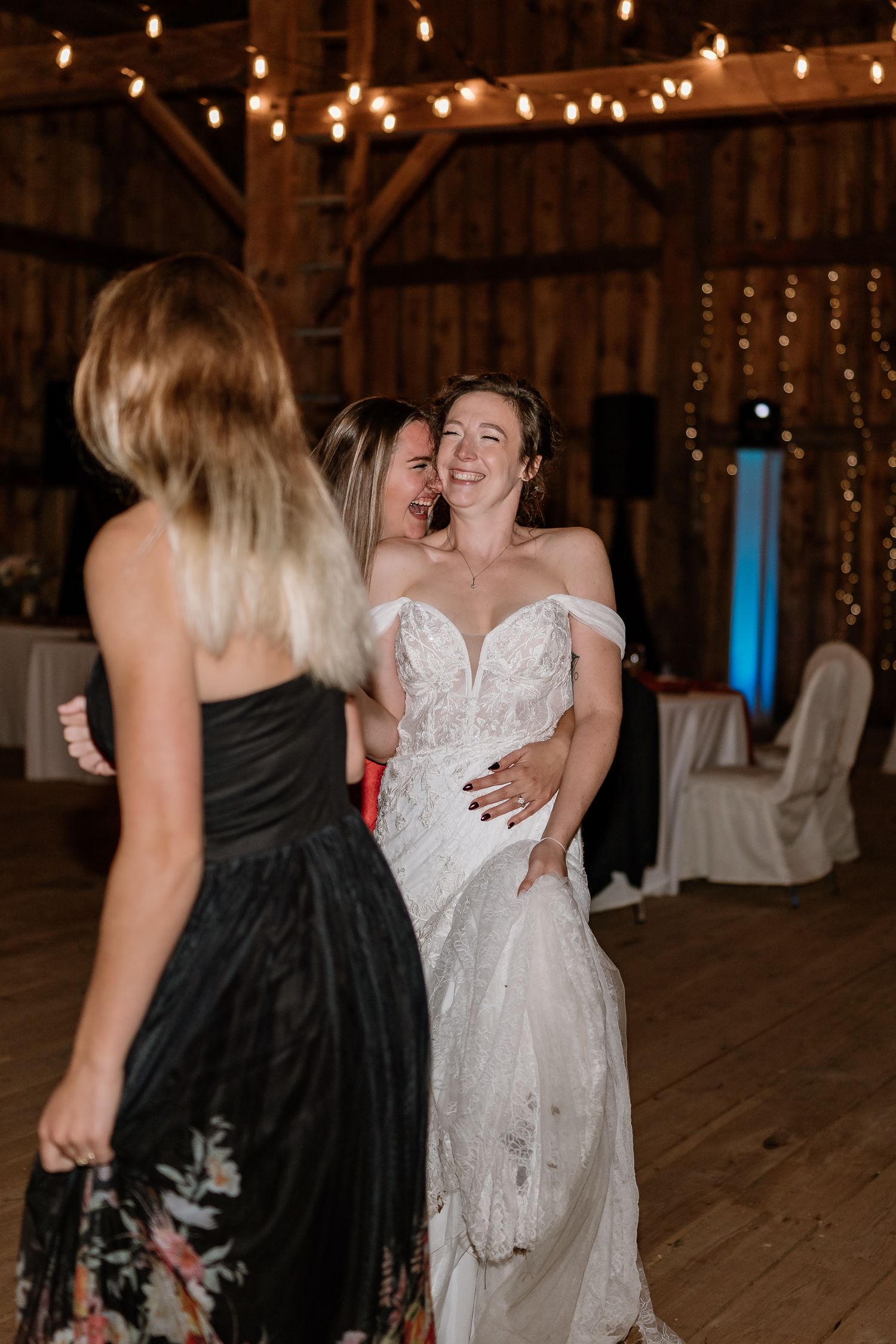 Wedding celebration in a rustic barn venue illuminated by string lights.