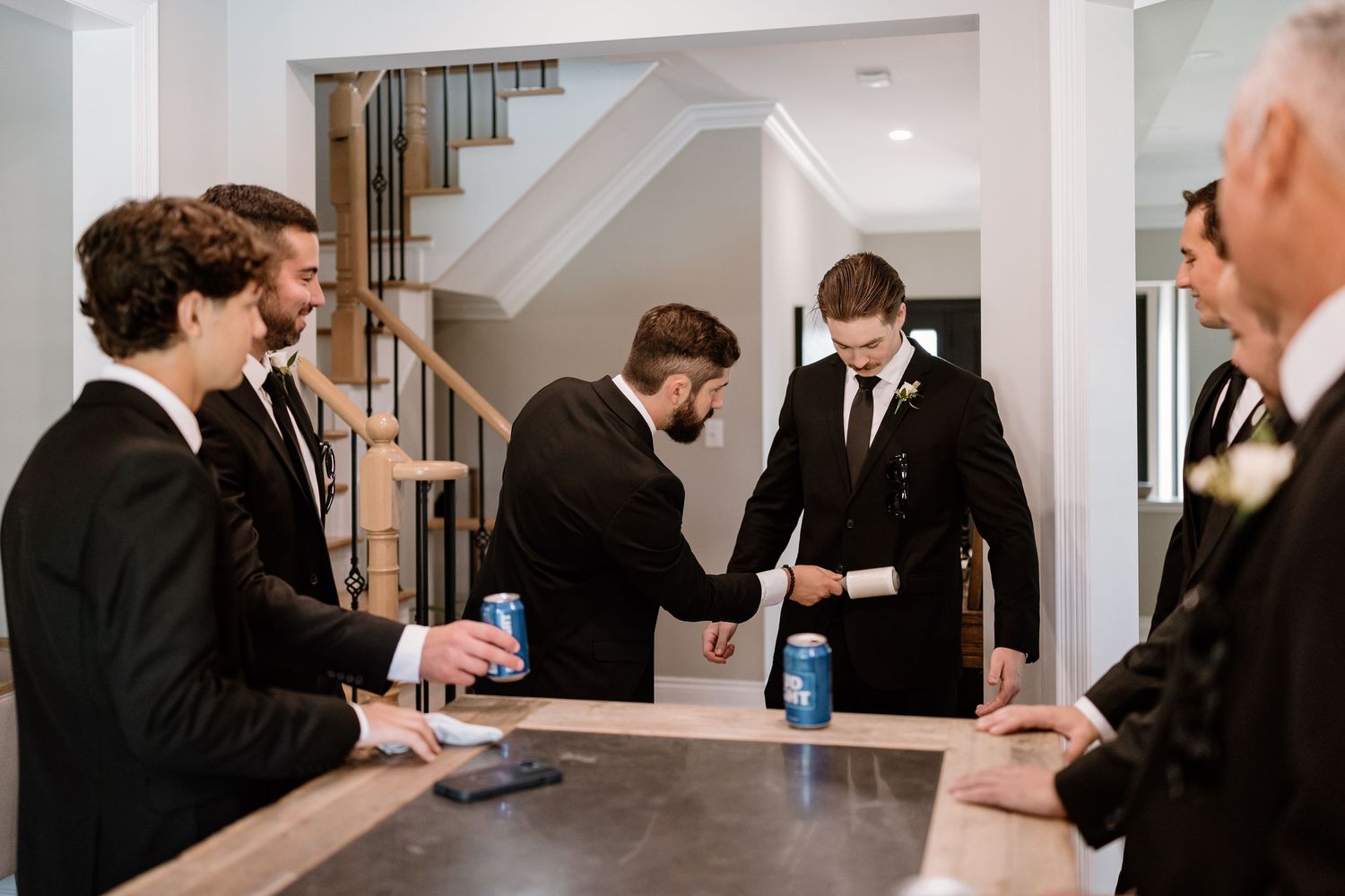 Group of men in suits gathered around a counter checking their phones.