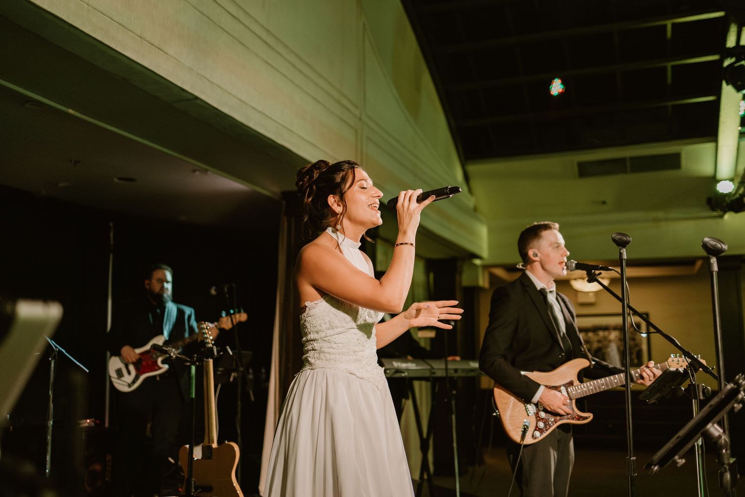 Band performing live music at a wedding reception with instruments and stage lighting.