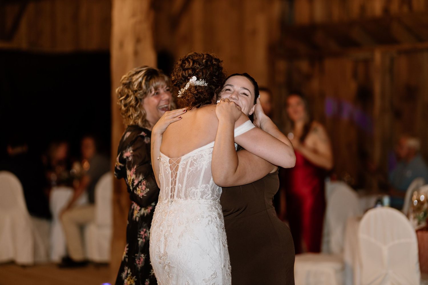 Couples sharing intimate dances during a barn wedding reception under warm lighting.