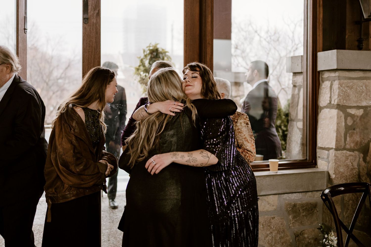 Wedding guests gather in an elegant indoor venue with rustic stone walls.