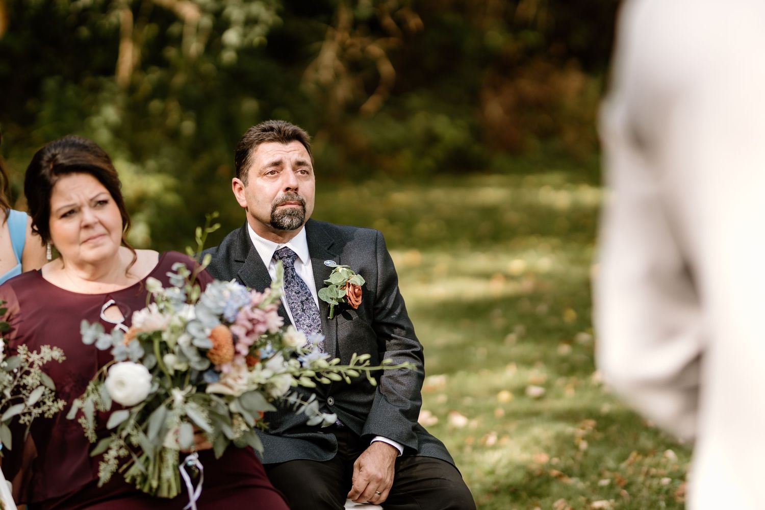 Wedding ceremony guests seated outdoors with elegant floral arrangements.