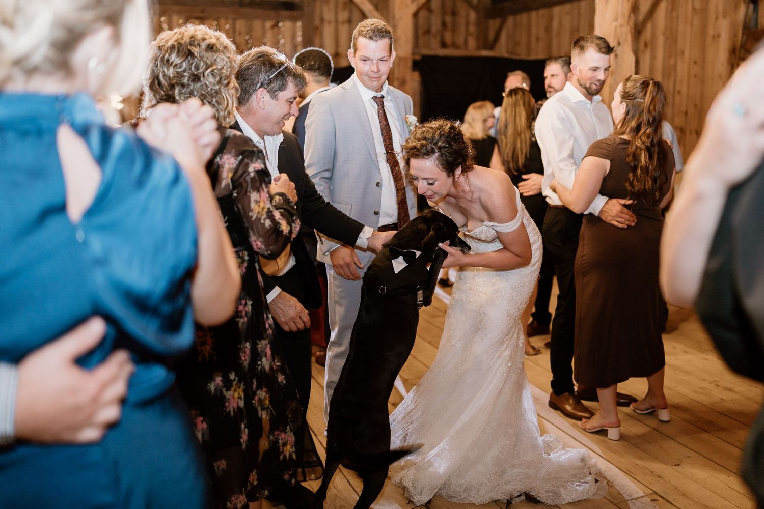 Wedding party dancing and celebrating on the wooden dance floor of a rustic barn venue.