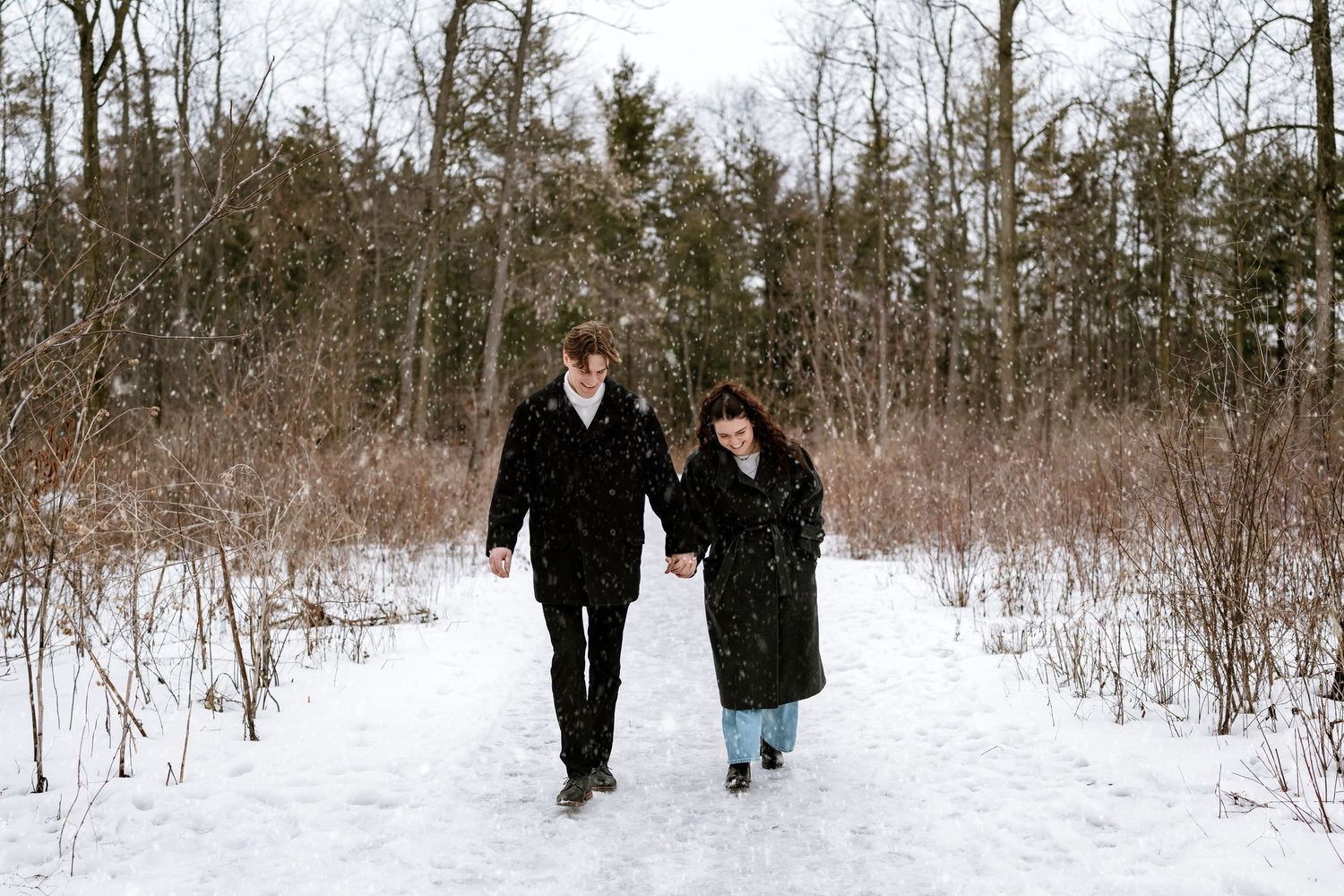 A distant view of people walking through a snow-covered forest path.