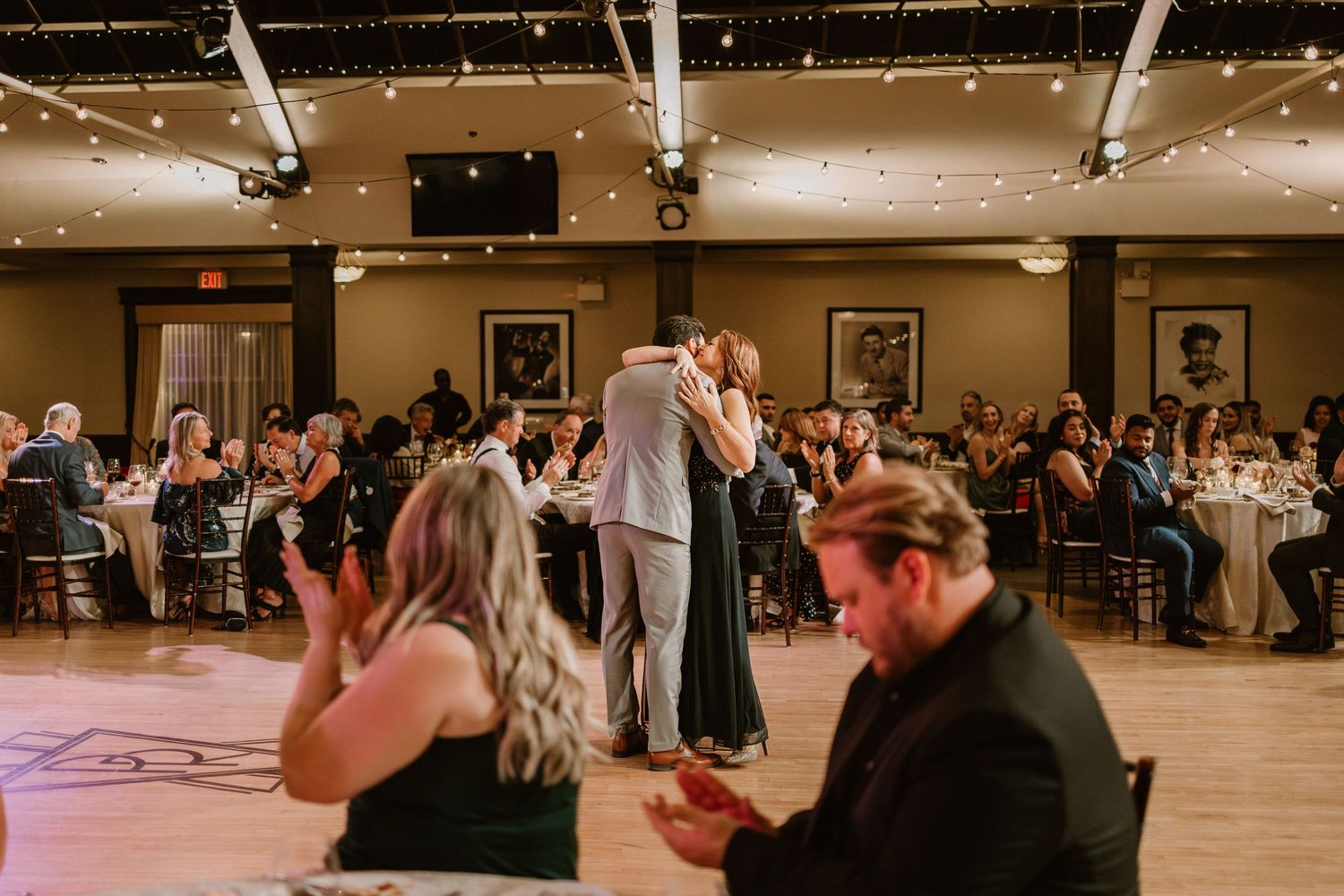 Large banquet hall filled with wedding guests during an evening reception celebration.