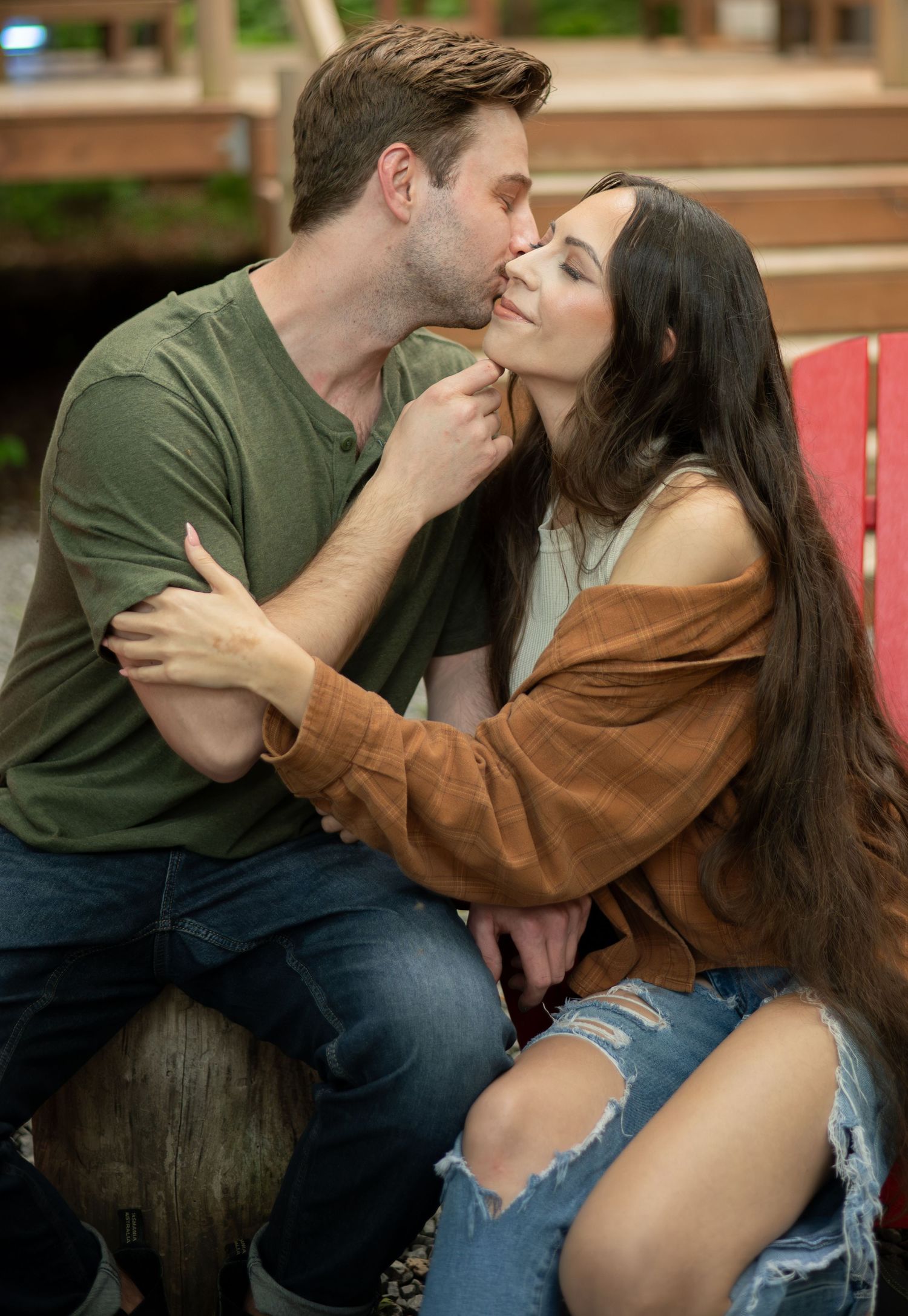A couple sharing intimate moments on outdoor wooden furniture.