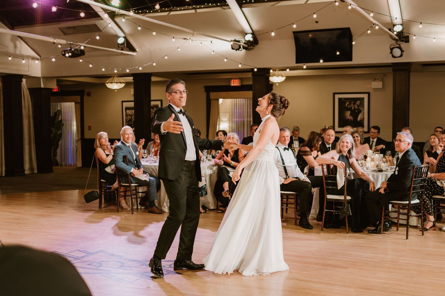 Wedding party performs special dances while guests watch from decorated reception tables.