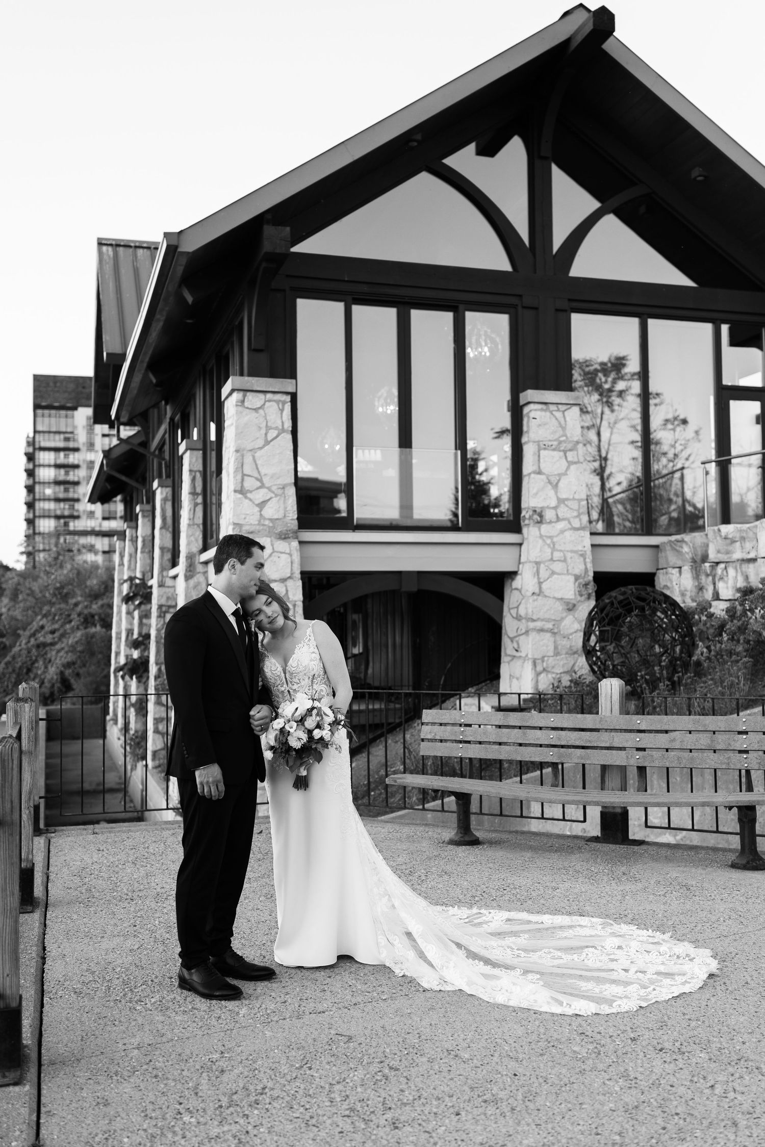 Elegant wedding portraits taken in front of stone pavilion with lake backdrop.