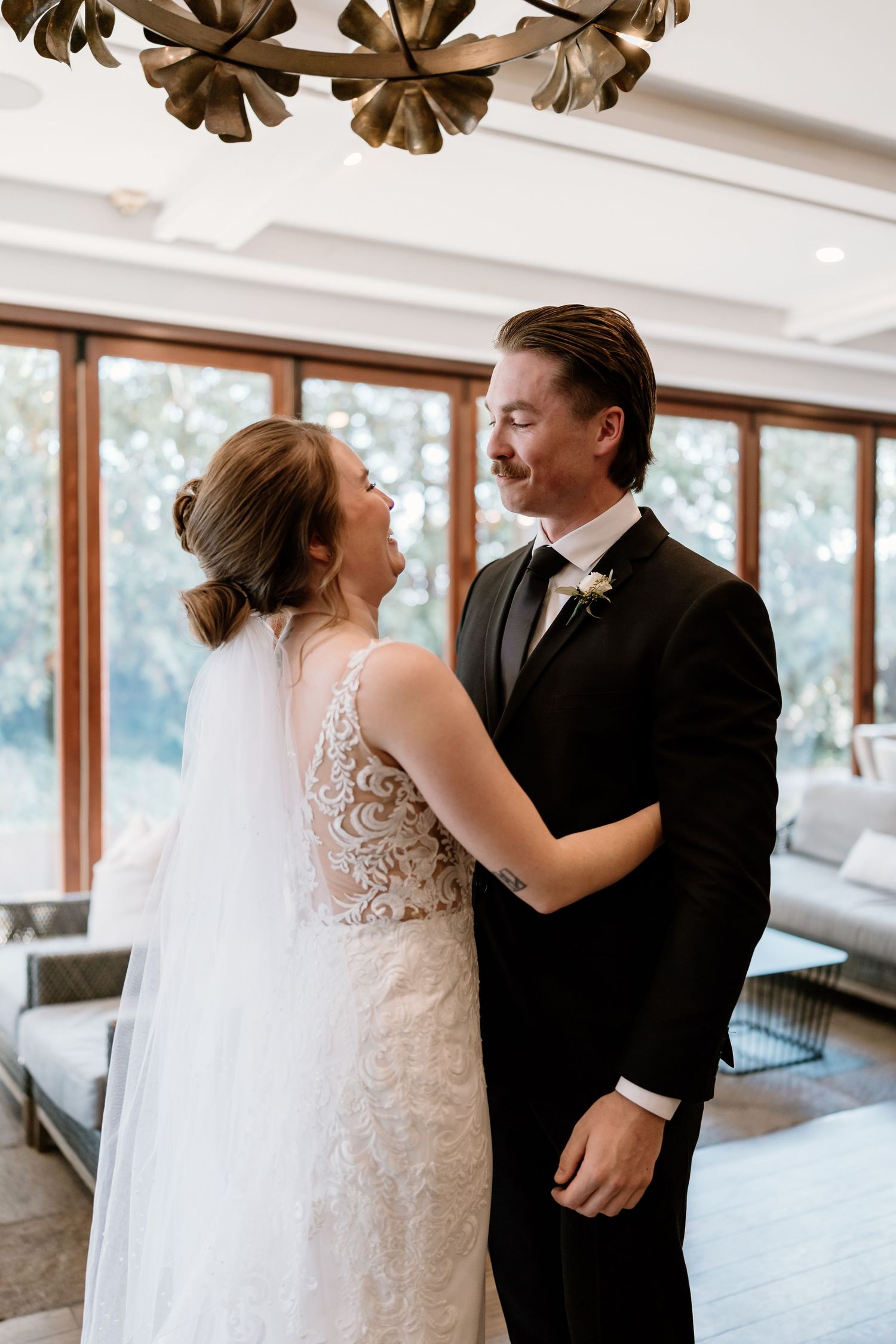 A romantic wedding moment captured under a decorative chandelier.
