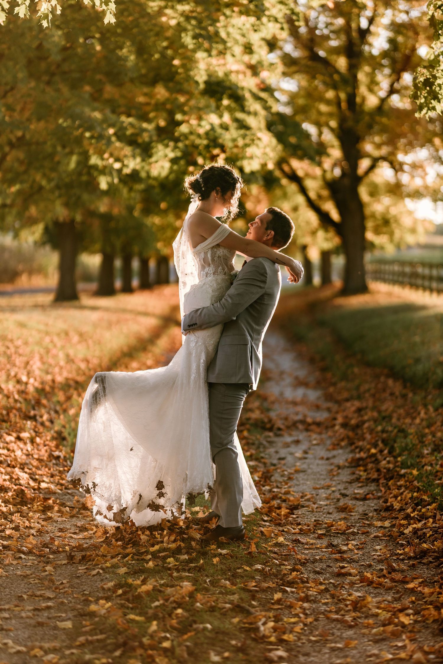 Romantic wedding dance captured in a golden autumn setting with fallen leaves.