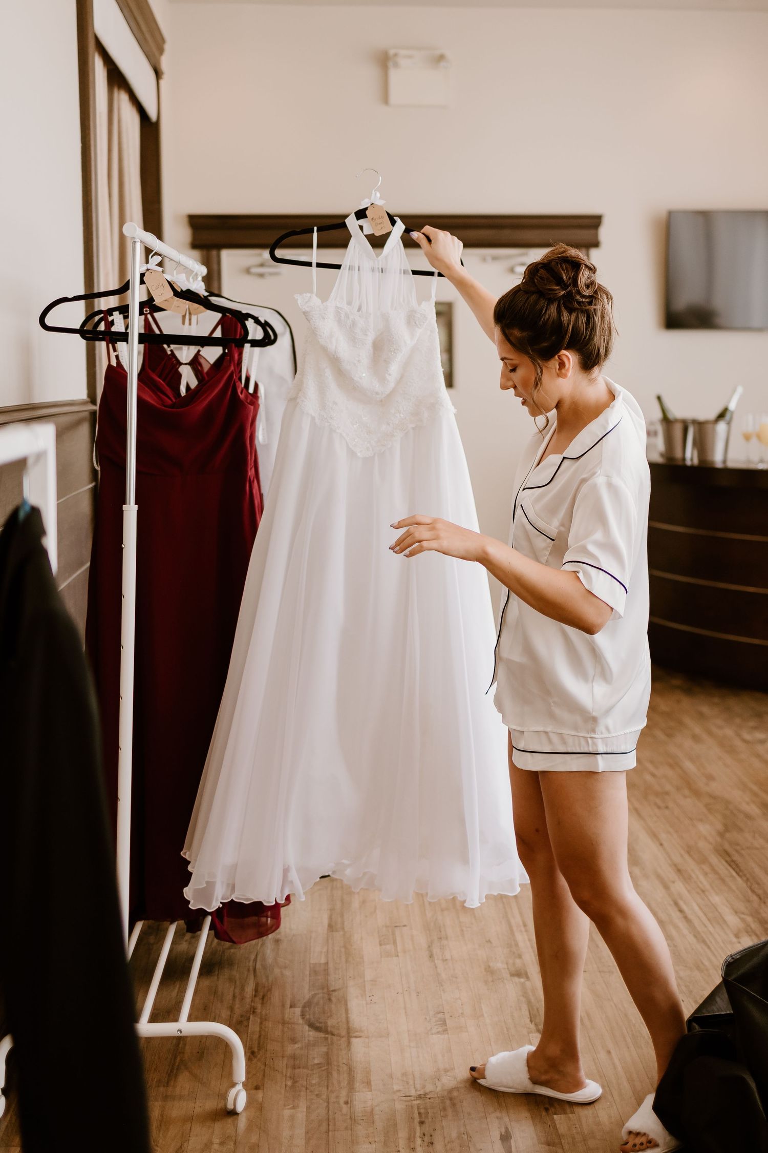 White wedding dress hangs on display while someone in pajamas examines the details.