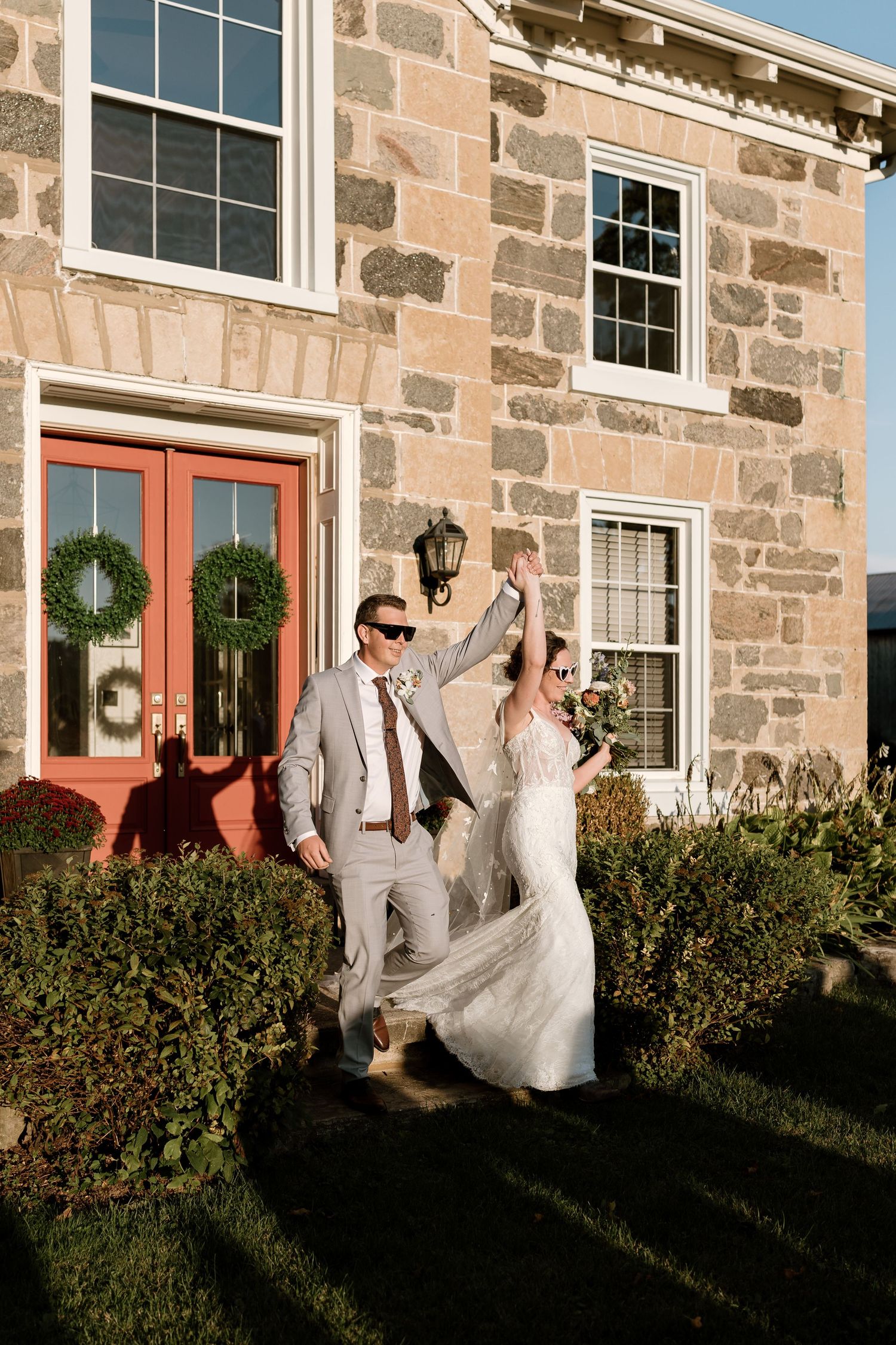 Wedding celebration outside a historic stone building with joyful dancing and festivities.